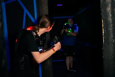Lasertag-Spielerin zielt hinter einer Säule in der Arena