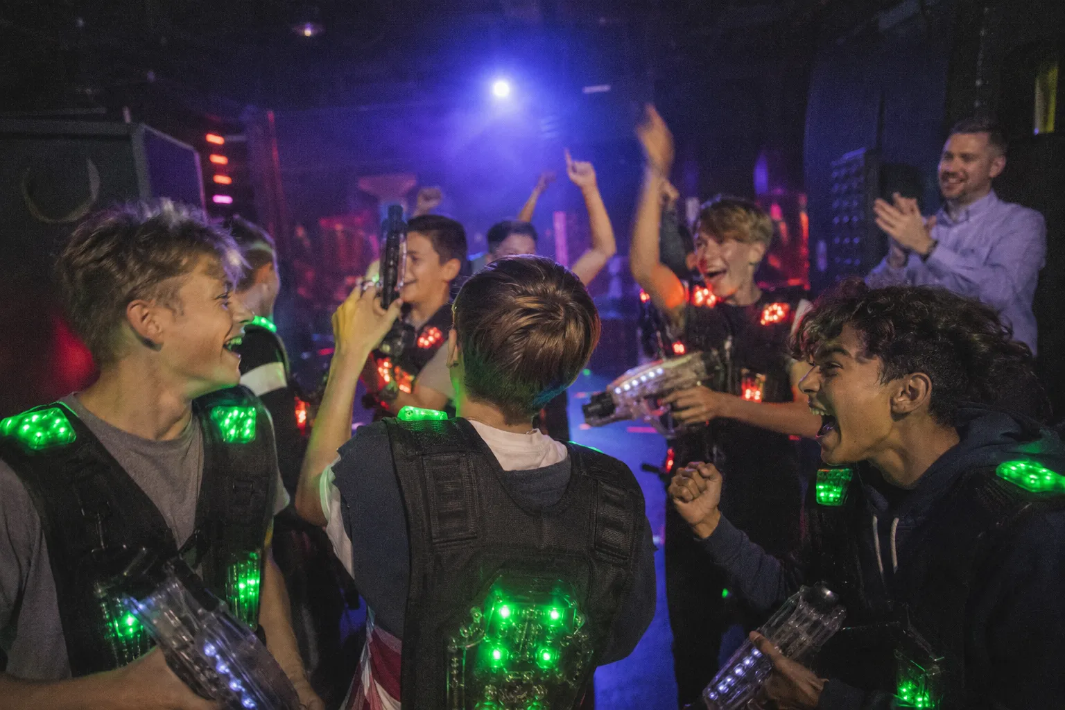 Schulklasse jubelt nach einer Lasertag-Runde in der dunklen Arena